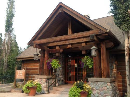 A rustic lodge entrance with wooden beams, stone accents, and hanging flower baskets.