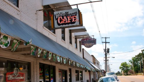 Exterior view of White House Cafe with signage and decorative banners along a sunny street.
