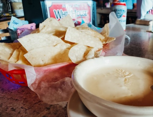 A basket of tortilla chips next to a bowl of creamy dip on a restaurant table.