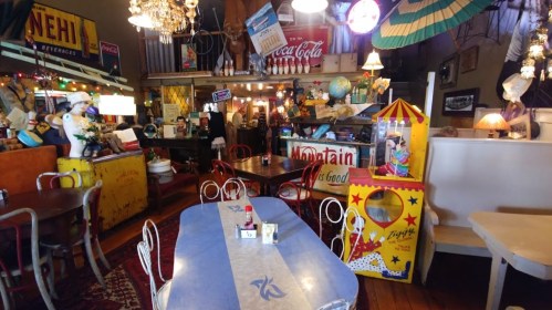 A quirky diner with vintage decor, colorful tables, and eclectic memorabilia, creating a nostalgic atmosphere.