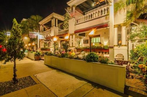 A charming restaurant exterior at night, featuring outdoor seating, decorative plants, and lit torches.