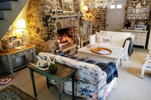 Cozy living room with a stone fireplace, comfortable seating, and festive decor, creating a warm, inviting atmosphere.