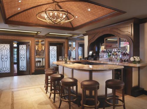 Elegant bar area with a curved counter, wooden stools, and decorative lighting in a stylish interior setting.