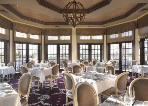 Elegant restaurant interior with round tables, white tablecloths, and large windows offering a scenic view.