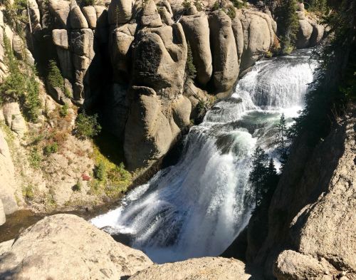 A scenic waterfall cascading over rocky cliffs, surrounded by lush greenery and rugged terrain.
