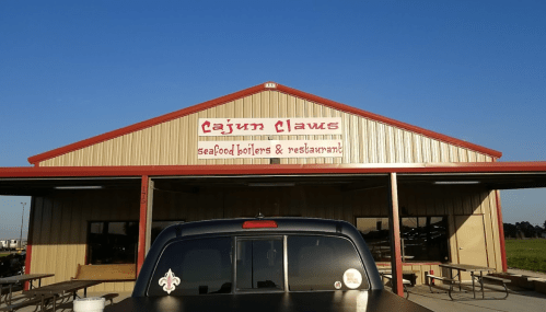 Exterior of Cajun Claws seafood restaurant with a clear blue sky and a parked truck in front.