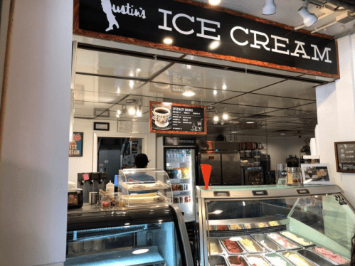 A vibrant ice cream shop with a display of colorful ice cream flavors and a menu board in the background.