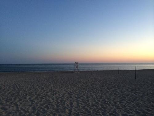A serene beach at dusk, featuring a lifeguard tower and calm waves under a colorful sky.