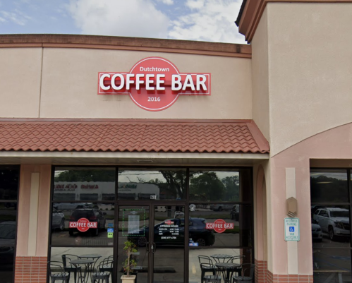 Exterior of Dutchtown Coffee Bar, featuring a red sign and glass entrance, with outdoor seating visible.