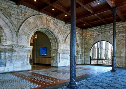 Interior view of a historic building featuring stone arches, wooden beams, and decorative tile flooring.