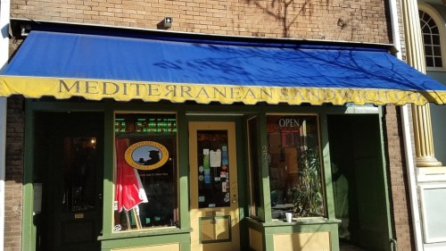 Exterior of Mediterranean Sandwich Co. with a blue awning and open sign, featuring a welcoming storefront.
