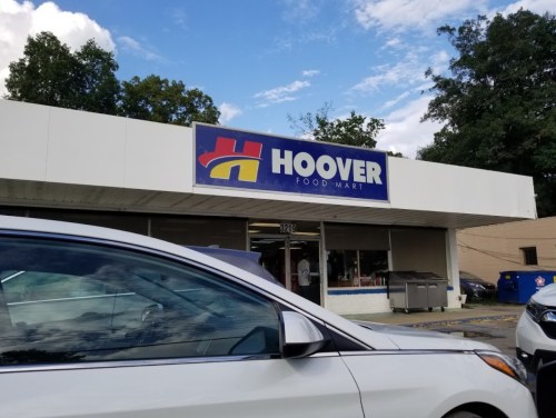Exterior of Hoover Food Mart with a large sign, parked cars in front, and trees in the background.
