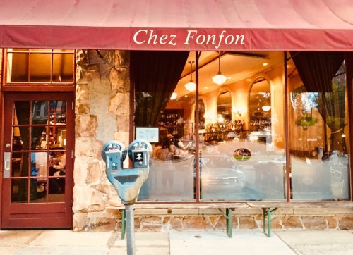 Exterior of Chez Fonfon restaurant with a red awning, large windows, and a parking meter in front.