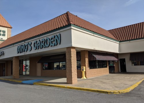Exterior of Ming's Garden restaurant, featuring a tiled roof and striped awning, located in a shopping plaza.