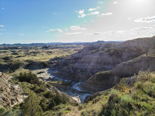 A panoramic view of rugged hills and valleys under a bright sky, showcasing the natural beauty of a landscape.