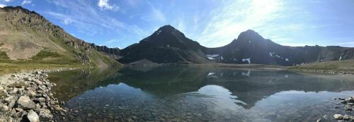 A serene mountain lake reflecting surrounding peaks under a clear blue sky.