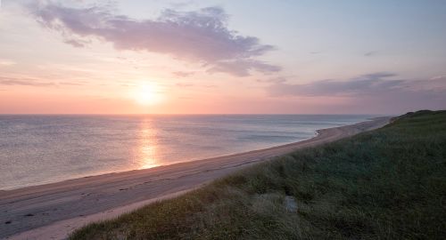 A serene beach at sunset, with gentle waves and a colorful sky reflecting on the water.