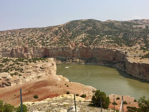 A scenic view of a winding river surrounded by rocky cliffs and arid hills under a clear sky.
