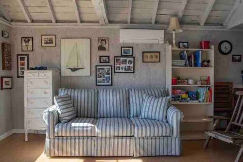 Cozy living room with a striped sofa, bookshelves, framed photos, and a ceiling fan in a light, airy space.