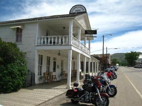 Historic inn with a porch, featuring parked motorcycles in front and a clear blue sky above.