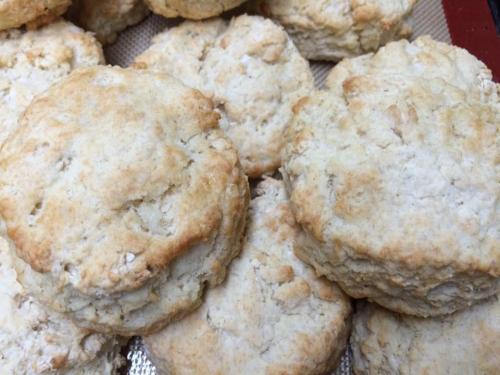 Freshly baked, golden-brown biscuits stacked on a baking sheet, showcasing a flaky texture.