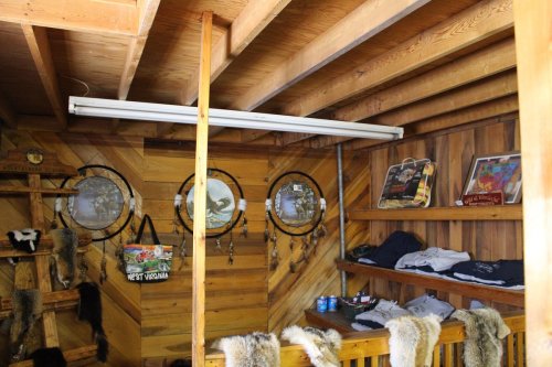Interior of a rustic wooden room with dreamcatchers, wall art, and shelves displaying clothing and items.