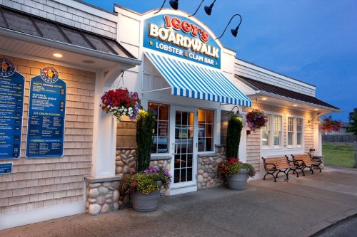 Exterior of Iggy's Boardwalk Lobster & Clam Bar, featuring a striped awning, flower baskets, and a welcoming entrance.