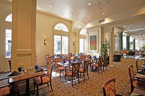 Elegant restaurant interior with tables set for dining, large windows, and decorative furnishings.