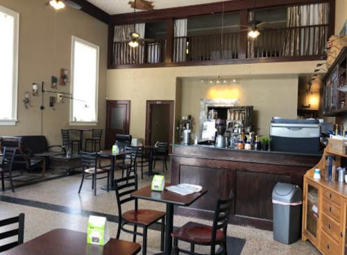 Cozy café interior with wooden furniture, a counter, and a loft area, featuring natural light and a relaxed atmosphere.
