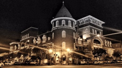 Historic building illuminated with decorative lights at night, featuring a tower and arched windows.