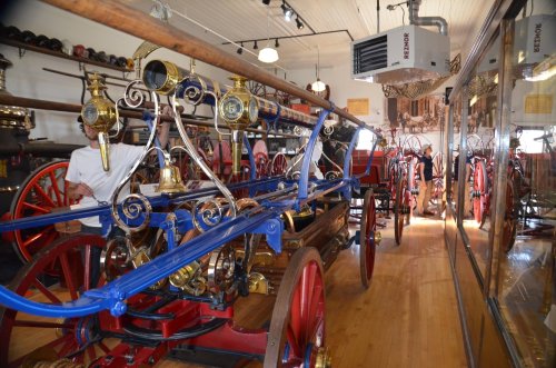 A vintage fire engine displayed in a museum, showcasing intricate brass details and wooden elements.