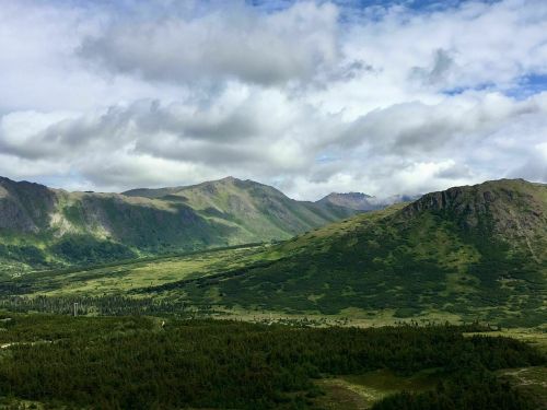 A scenic view of mountains and lush green valleys under a partly cloudy sky.