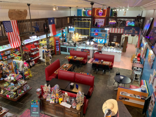 A colorful diner interior with red booths, vintage decor, and a variety of merchandise displayed on shelves.