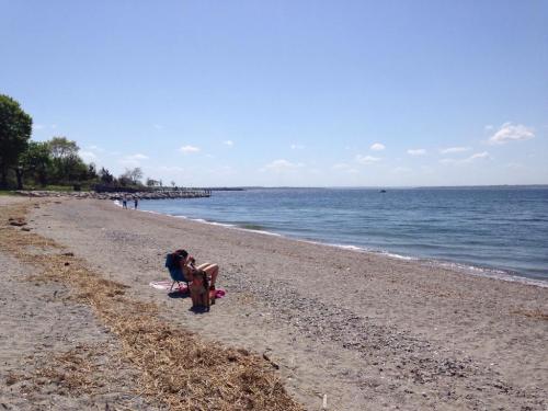 A sunny beach scene with a person relaxing on the sand, surrounded by water and distant shoreline.