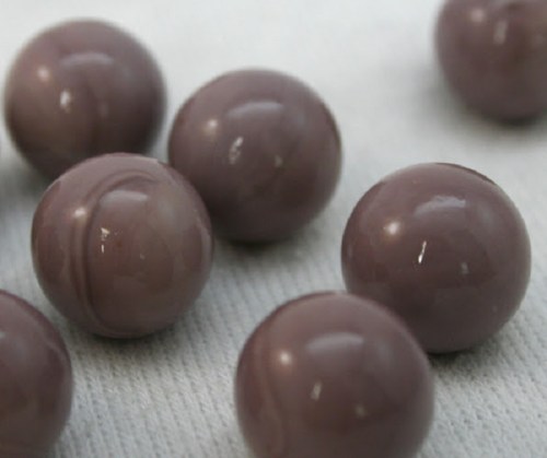 A close-up of several glossy, purple marbles arranged on a light surface.