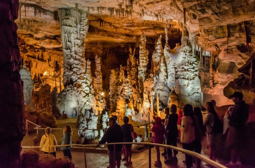 Visitors explore a stunning cave filled with illuminated stalagmites and stalactites, showcasing natural rock formations.