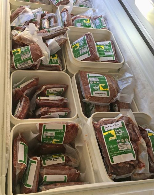 A freezer filled with neatly packaged beef products in white containers, labeled with green and yellow tags.