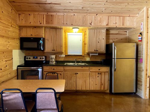 Cozy wooden kitchen with a table, appliances, and natural light from a window.