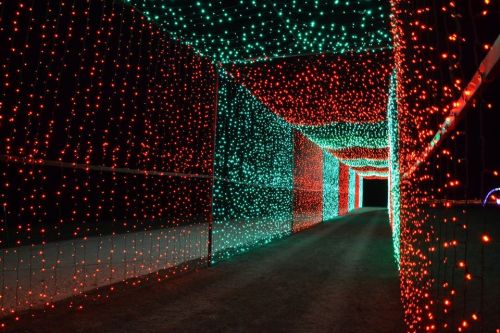 A brightly lit tunnel adorned with red and green lights, creating a festive atmosphere at night.