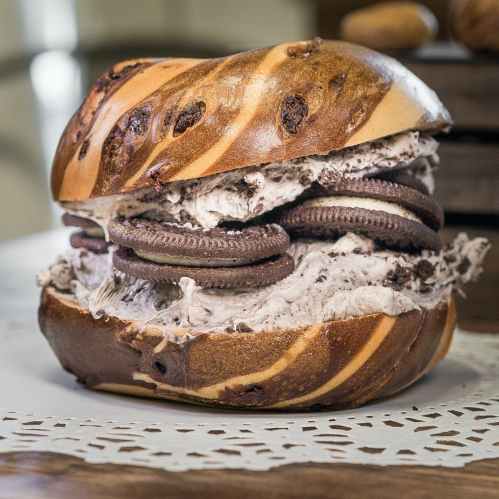 A large, swirled bagel filled with cookies and cream ice cream and Oreo cookies.