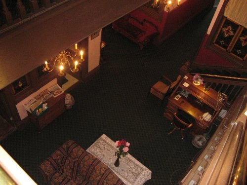 A cozy interior view from above, featuring a sofa, a table with flowers, and a wooden desk in a warmly lit room.