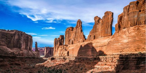 A stunning view of towering red rock formations under a blue sky, with shadows cast in a desert landscape.