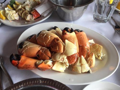 A plate of cooked crab claws, some cracked open, garnished with lemon slices and served on a white tablecloth.