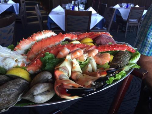 A large seafood platter featuring crab legs, shrimp, oysters, and lemon, garnished with lettuce.