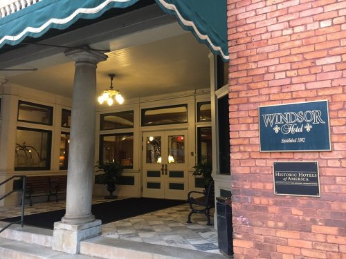 Entrance of the Windsor Hotel, featuring a green awning, brick facade, and historic signage. Established in 1902.