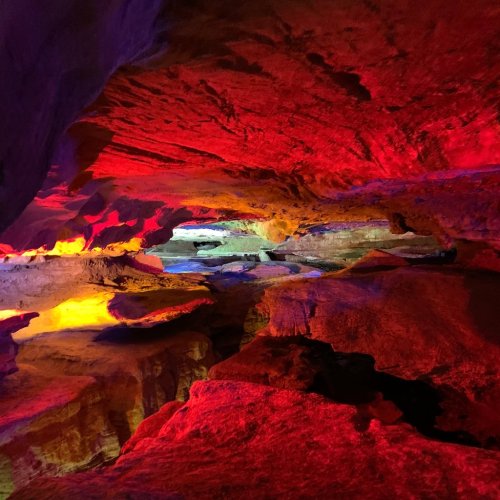 A colorful cave interior with vibrant red, orange, and blue lighting illuminating the rock formations.