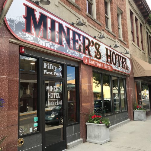 Exterior of Miner's Hotel, a boutique hotel with a stylish sign, located on a street with brick buildings.