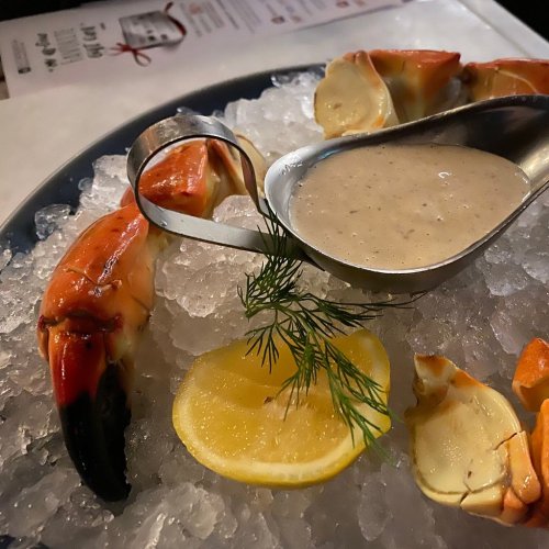 A plate of seafood claws on ice, garnished with lemon slices and a small bowl of dipping sauce.
