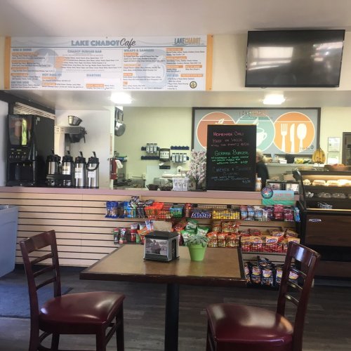 Interior of Lake Chabot Cafe with a menu board, snack display, and empty tables. Bright and inviting atmosphere.