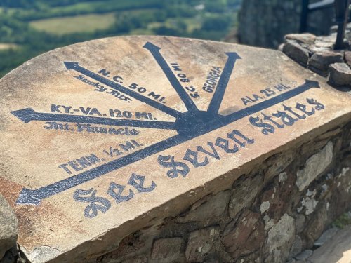 A stone marker displaying directional distances to various states, with "See Seven States" inscribed prominently.